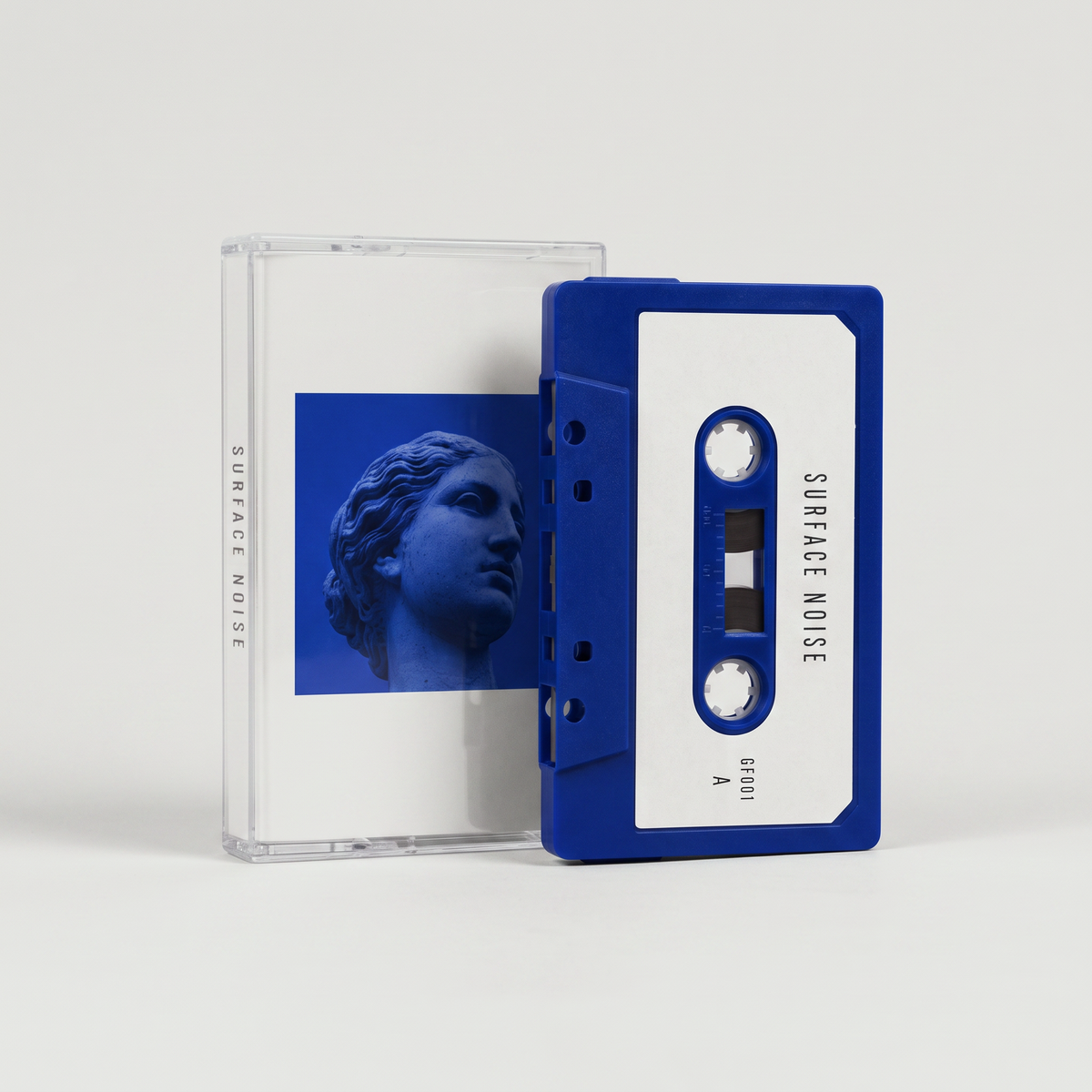 Surface Noise cassette: cobalt shell with an off-white label, clear case with the Venus artwork J-card behind it